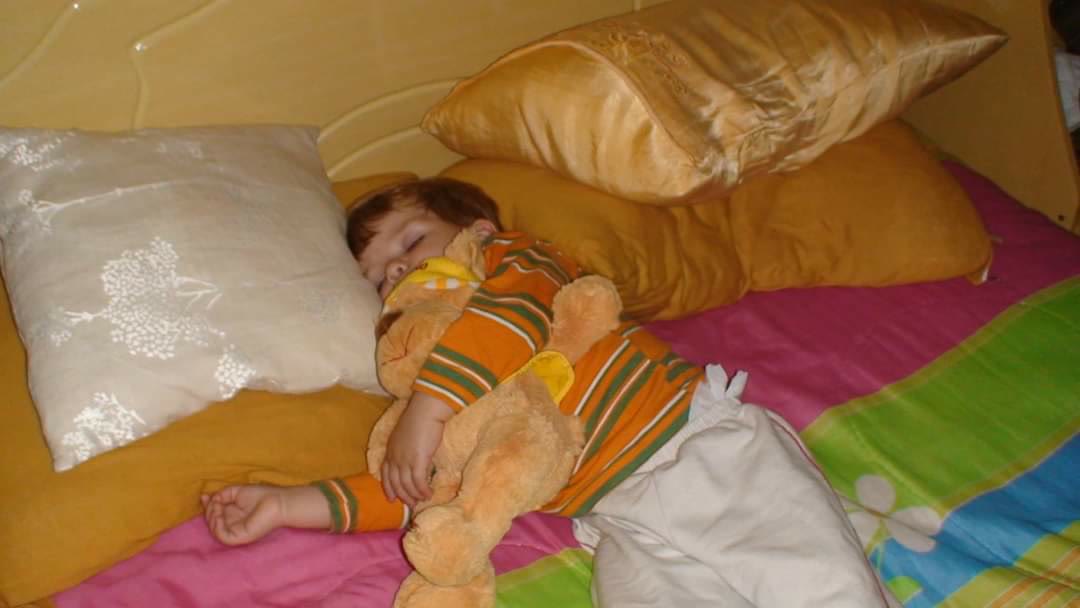 Criança pequena dormindo abraçada num bicho de pelúcia.