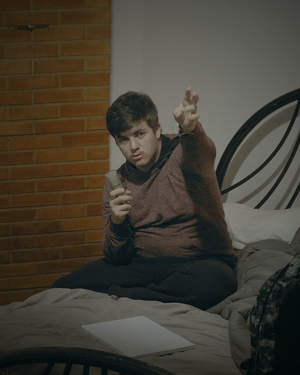 Johann sentado na cama, apontando para a câmera.
